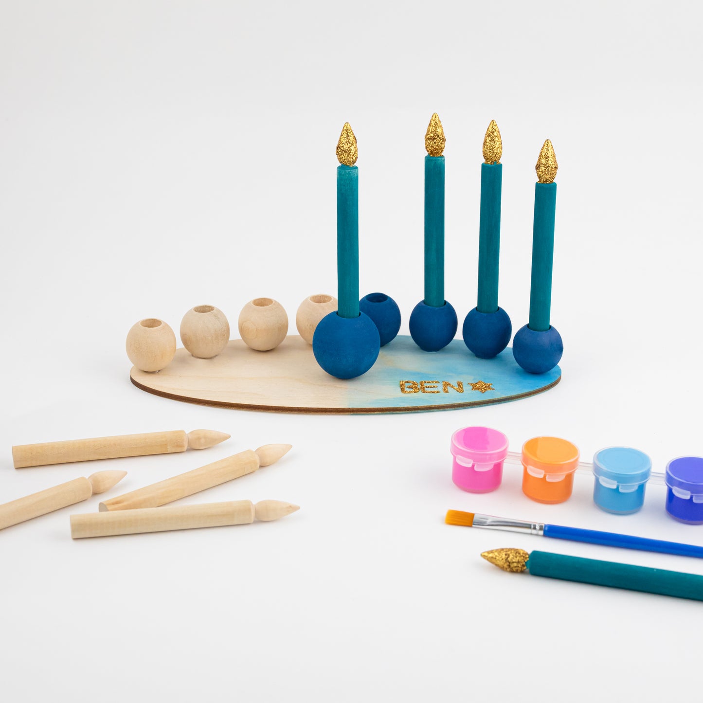 "My DIY Menorah Kit: Discover What's Inside. ALT: Open box revealing kit components for creating a personalized menorah. Wooden play menorah elegantly assembled in the backdrop, inspiring Hanukkah creativity."